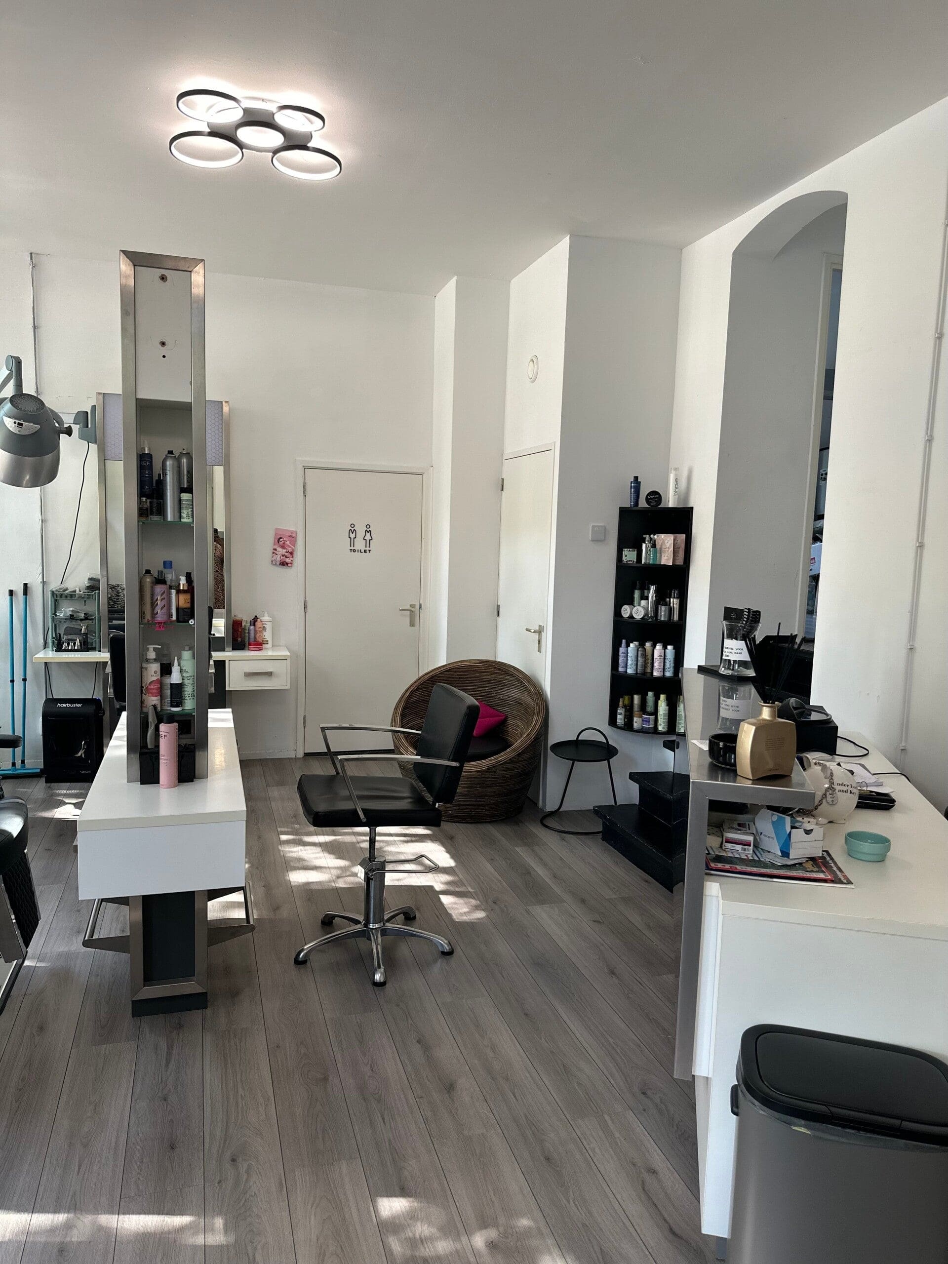 De kapstoel en de spiegels in de salon, met de productkast langs de witte wand.